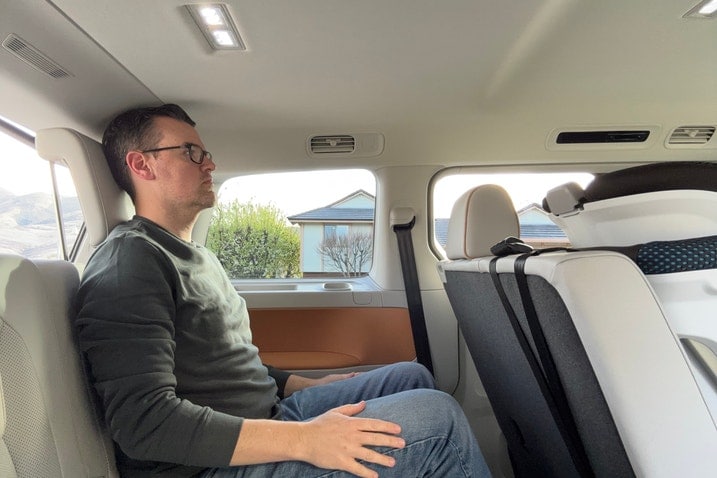A 6-foot-3 man in VW ID. Buzz third row fully slid back