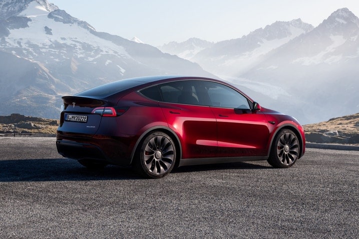 2023 Tesla Model Y Performance in red paint parked with snow-capped mountains in the background