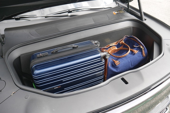 Rivian R1S frunk with floor propped up and two suitcases