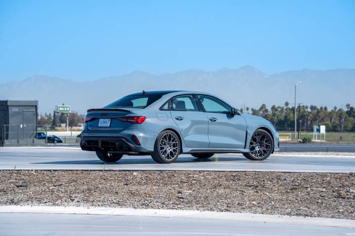 Rear three-quarter shot of a 2025 Audi RS 3 parked at a test track.